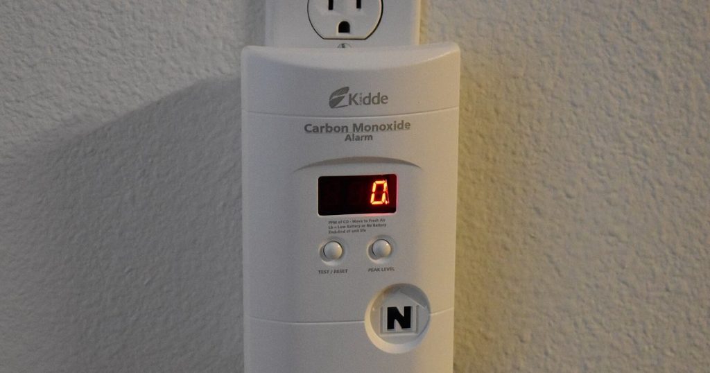 Plug-in carbon monoxide alarm with a digital display mounted on a wall outlet