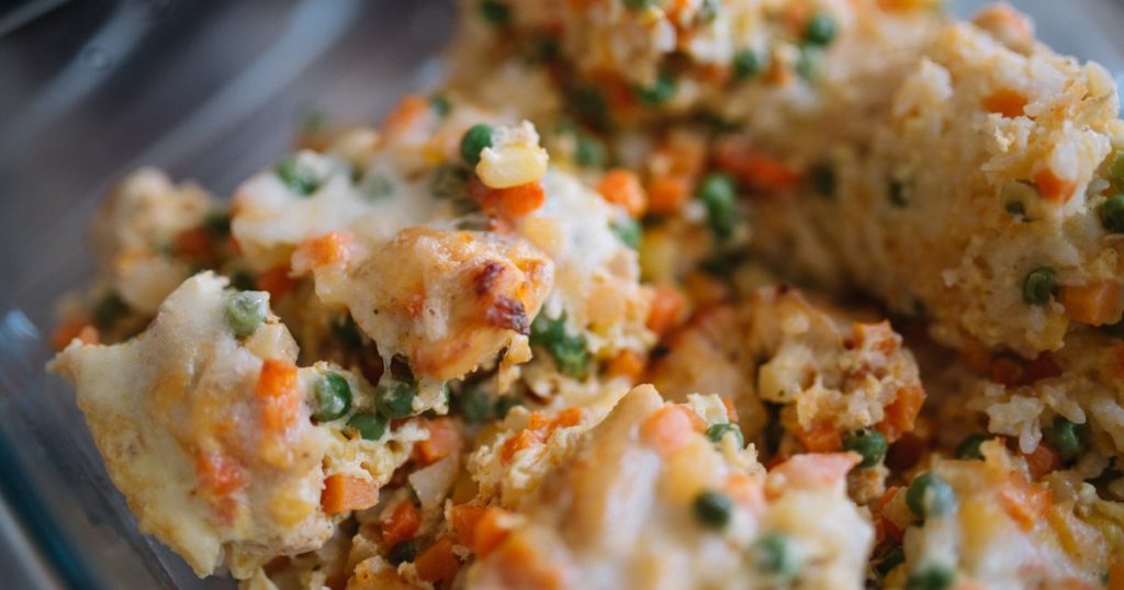 Vegetable casserole with carrots and peas in a clear glass baking dish