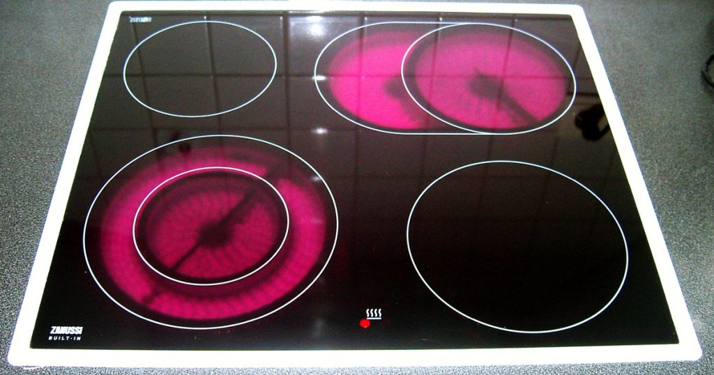 Glass-ceramic electric cooktop with three radiant elements glowing red under the glass