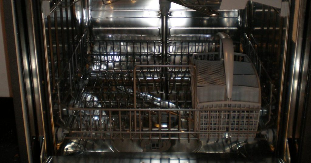 Open dishwasher showing the lower rack, the stainless tub and the edge of the door opening