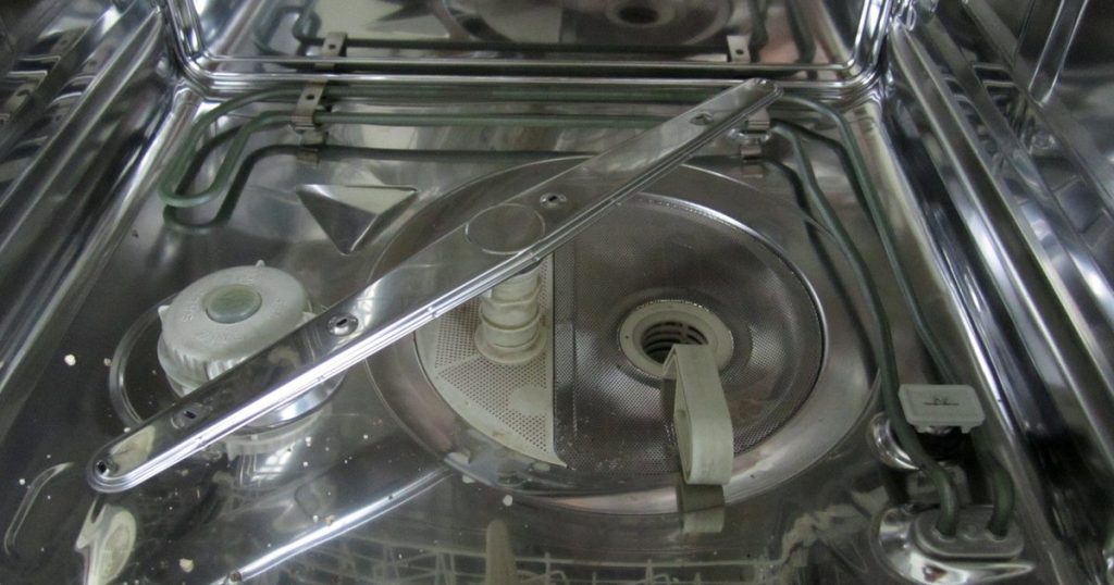 Inside a dishwasher tub, showing the loop-shaped heating element around the base