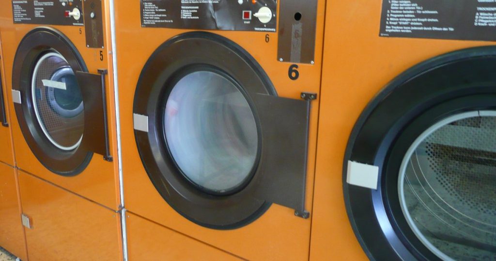 Row of front-load clothes dryers with their doors open, showing the drums inside