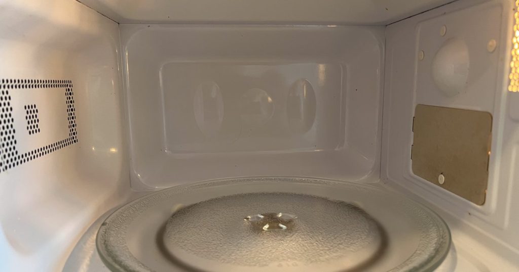 Inside an empty microwave oven, showing the glass turntable and the waveguide cover on the side wall