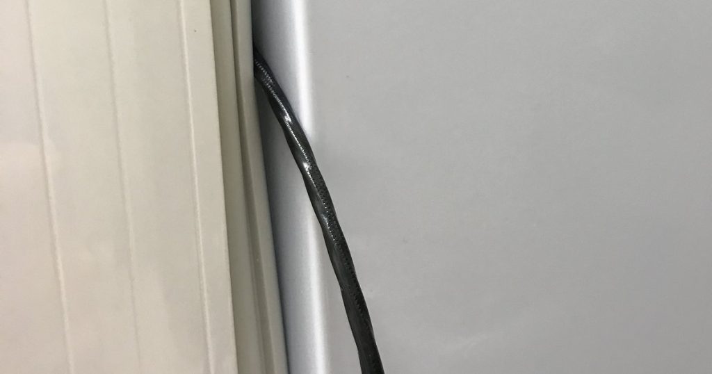 A cable pinched in a refrigerator door gasket, holding the seal away from the cabinet and leaving a gap for air