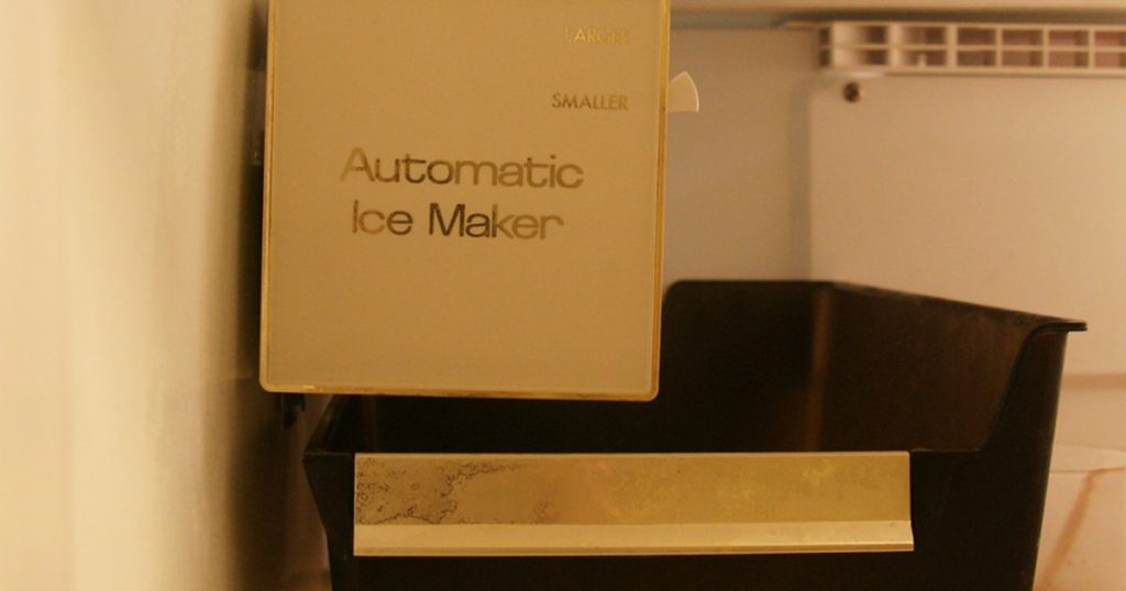 Empty ice bin under an automatic ice maker inside a refrigerator freezer