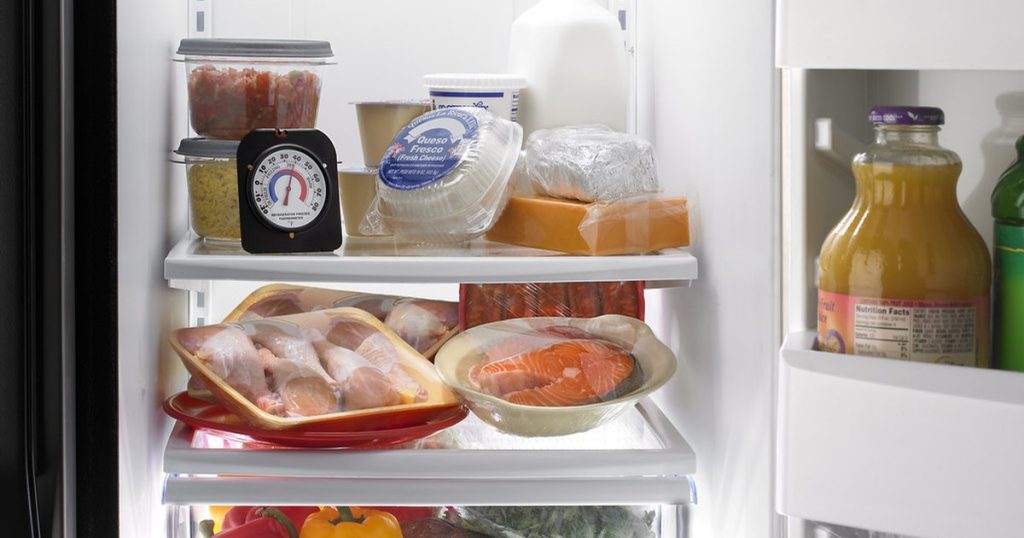 Open refrigerator with an appliance thermometer on the top shelf, used to check whether the fridge is cooling properly