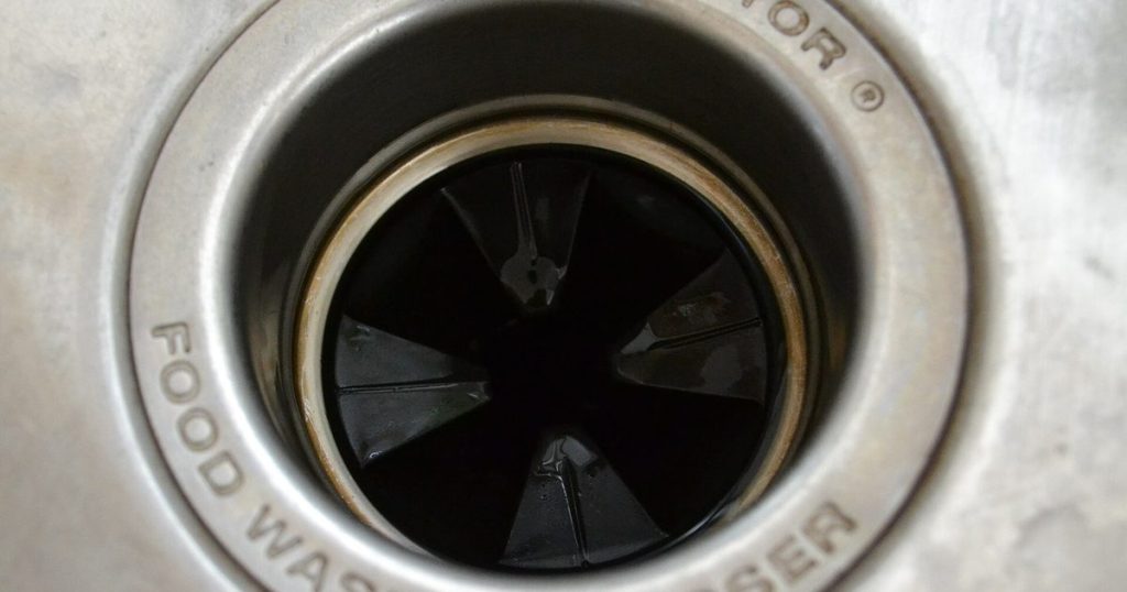 Looking down into a kitchen sink garbage disposal, with the rubber splash guard where food and odors collect