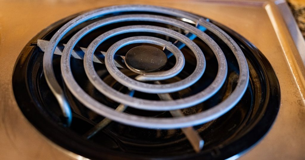 Electric coil stove burner sitting in a black drip pan on a range cooktop
