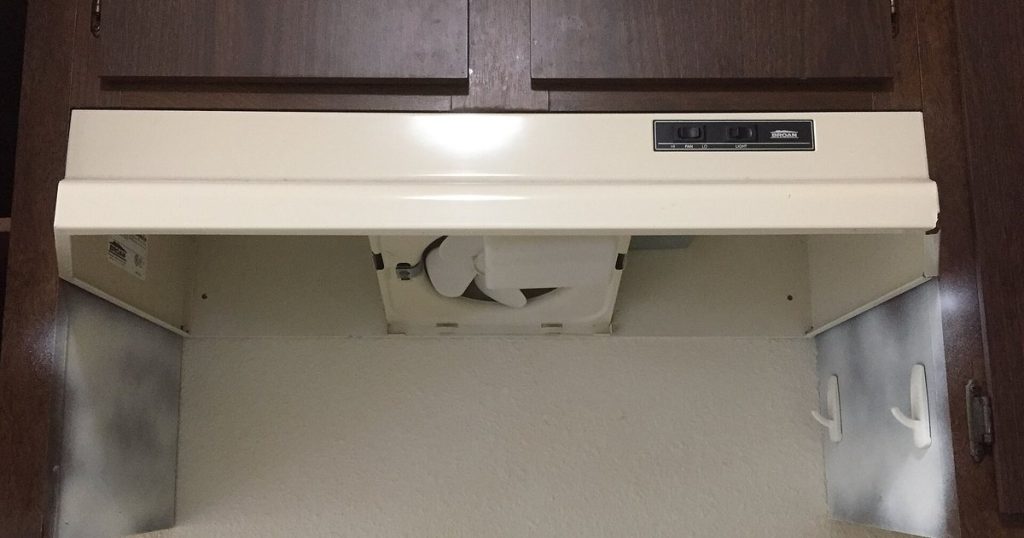 Under-cabinet range hood with the grease filters removed, showing the hood fan blower housing