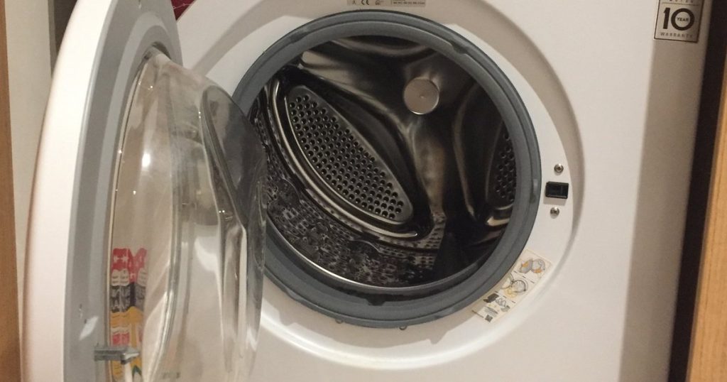 Front-load washing machine with the door open showing the empty steel drum